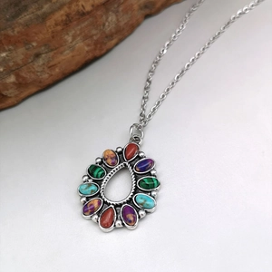 Macro shot of silver teardrop necklace with colorful turquoise and mixed gemstone inlay