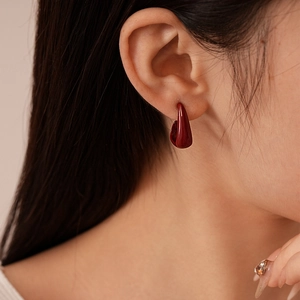 Gros plan de boucles d'oreilles clous en émail rouge foncé en forme de C, style rétro