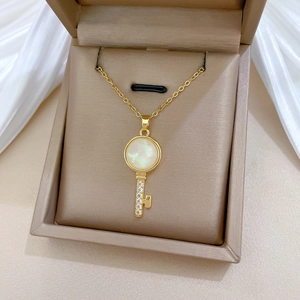 Close-up of golden key necklace with cat eye stone and zircon in a jewelry box