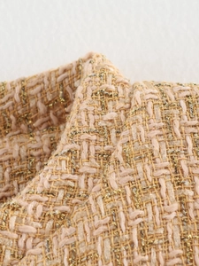 Close-up of elegant apricot tweed fabric with delicate gold metallic yarn texture
