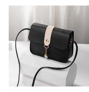 Detail of black pebbled leather crossbody bag with pearl charm and gold buckle accents
