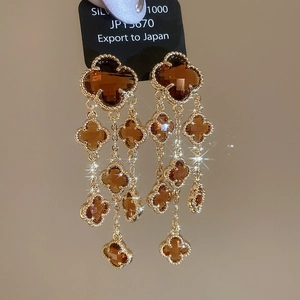 Macro shot of gold-plated clover tassel earrings with amber crystal stones and fringe