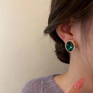 Gros plan de boucles d'oreilles émeraude vintage avec cristaux sur monture dorée portée