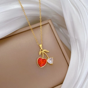 Macro shot of gold cherry pendant with red and clear heart stones on white silk