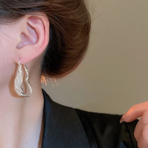 Close-up of elegant silver mesh earrings with pavé diamonds on a model's ear