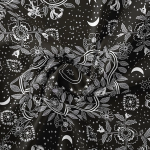Detail of bohemian black fabric with white floral, moon and star prints and soft texture