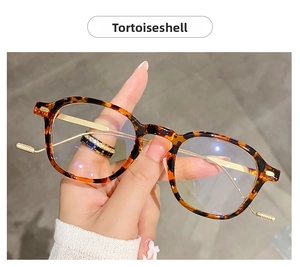 Detail of tortoiseshell round frames with slim gold metal temples held by hand