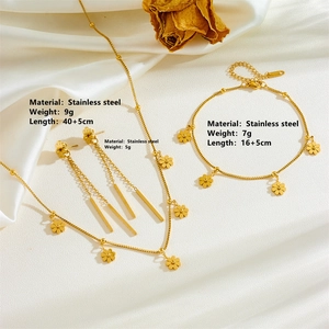 Golden stainless steel jewelry set featuring daisy pendants and tassel details on silk