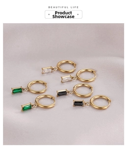 Close-up of gold hoop earrings with emerald, clear, and black rectangle zircon pendants