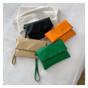 Vista plana de bolsos de sobre minimalistas en colores negro, naranja, dorado y verde de cuero