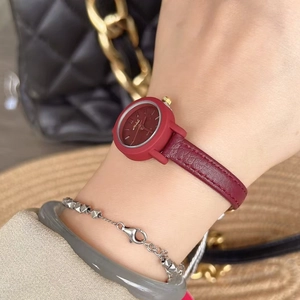 Close-up of a women's round red leather watch styled with fashion accessories