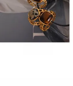 Close-up of gold chain rings with square leopard stone and tiger eye in vintage luxury style