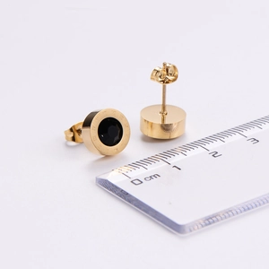 Macro shot of gold-plated titanium earrings with roman numerals and black center inlay