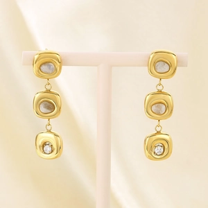 Detail of gold-plated square drop earrings featuring cat-eye stones and cubic zirconia