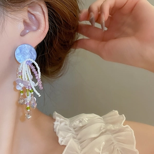 Détails de boucles d'oreilles à pompons bohèmes avec base marbrée bleue et fleurs mauves