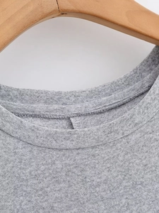 Detail of grey knitted dress neckline with fine texture and stitching on wood hanger