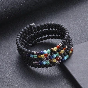 Macro shot of black lava stone and colorful seven chakra beads on a multilayered bracelet