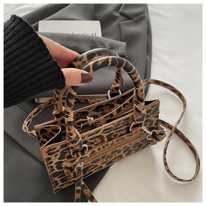 Dettaglio della borsa leopardata con trama e tracolla su sfondo di blazer grigio