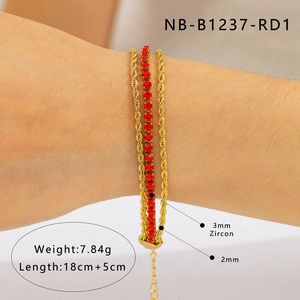 Détail d'un bracelet triple doré orné de zircons rouges de 3mm porté sur le poignet
