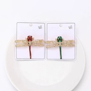 Detail of red and green enamel dragonfly brooches with gold wings and rhinestones
