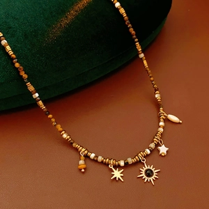 Detailed macro shot of vintage beaded necklace with sun and star pendants on green velvet