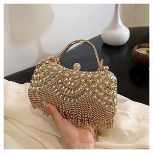 Detailed view of golden rhinestone evening clutch with long tassels and crystal ball clasp