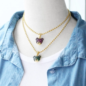 Detail of layered gold bear pendants with purple and green crystals on ball chains
