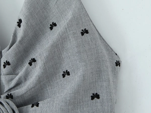 Macro shot of grey herringbone fabric with black velvet 3D butterfly embroidery details