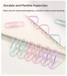 Close-up of heart-shaped and oval macaron metal paper clips on grid notebook
