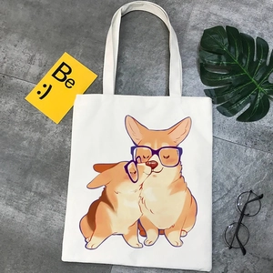 Detail shot of a white canvas tote bag with a cute Corgi print and Be :) card accessory