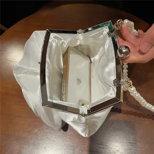 Interior detail of white satin evening bag with pearl strap holding a smartphone