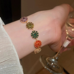 Detail of 18k gold plated bracelet with colorful zircon flower pendants on a female wrist