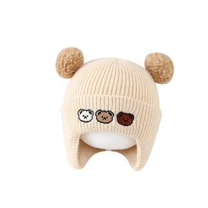 Bonnet tricoté crème pour bébé avec broderie ours et deux pompons marrons à oreillettes