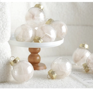 Detail of transparent Christmas ball with soft champagne feathers and golden cap