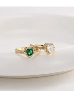 Close-up of heart-shaped green and clear zircon rings with gold band and pavé diamonds