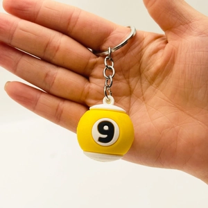 Close-up of yellow number 9 billiard ball keychain with metal chain in hand
