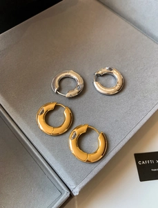 Detailed macro view of gold and silver plated hoop earrings with cubic zirconia inlay