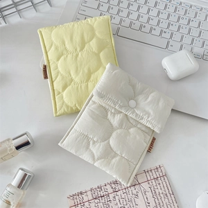 Detail of heart-quilted fabric organizer pouch with snap button on a bright desk