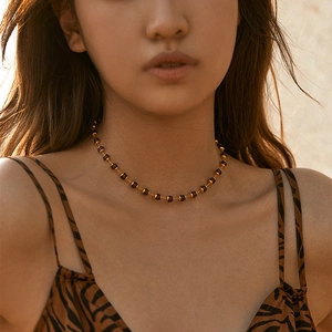 Close-up of a vintage gold plated necklace with dark brown beads on a model