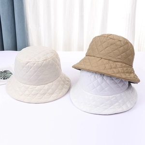 Detailed view of quilted bucket hats in cream, khaki, and white showing diamond stitching