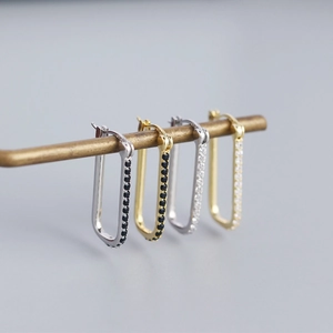 Macro detail of geometric S925 silver hoop earrings with inlaid black and clear crystals