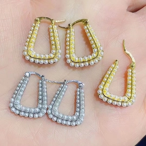 Detail of 18K gold and silver plated U-shaped earrings with faux pearl inlay