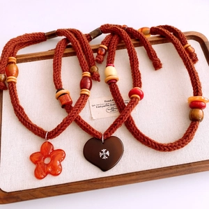 Detail view of heart and flower pendants on braided cords with beads on a display tray