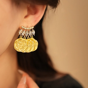 Close-up of vintage gold coin tassel earrings with sparkling marquise crystal on model