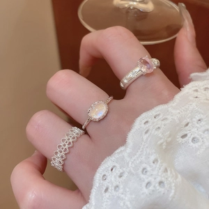Close-up of three silver-tone stacked rings with opal and star detailing on model finger
