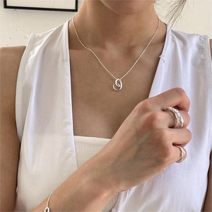 Close-up of minimalist S925 silver necklace and matching rings worn by a model