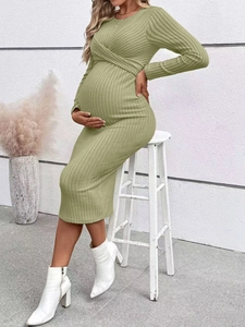 Side view of a pregnant model in a green long-sleeve knit dress with ribbed texture