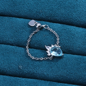Detail of adjustable silver chain ring featuring a teardrop blue stone and heart charm