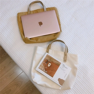 Detailed view of ginger and beige canvas tote bags with brown leather handles and rivets