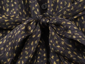 Detailed close-up of leopard print fabric with gold lurex threads and button tie closure